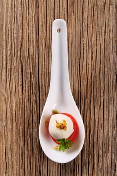 Baby mozzarella and tomato on porcelain spoon