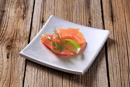Thin slice of smoked salmon and wedge of  lime