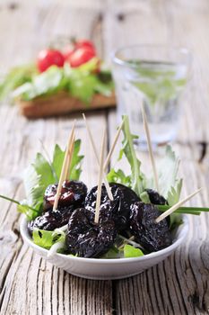 Glazed prunes on a nest of salad greens 