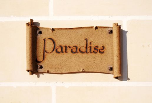 Ceramic sign reading Paradise on a wall