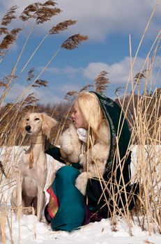 A blonde girl and a saluki in canes in winter
