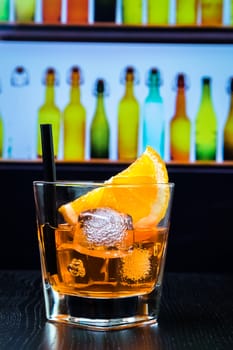 glass of spritz aperitif aperol cocktail with orange slices and ice cubes on bar table, disco lounge bar atmosphere background, lounge bar concept