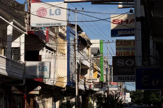 MANADO, NORTH SULAWESI, INDONESIA - AUGUST 5, 2015:  Billboards and communications cables on Manado street on August 5, 2015 in Manado, North Sulawesi, Indonesia