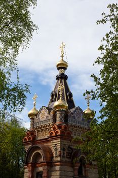 Red orthodox church with traditional decoration in a park
