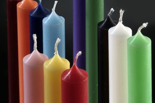 group of colorful cylindrical candles on a black background