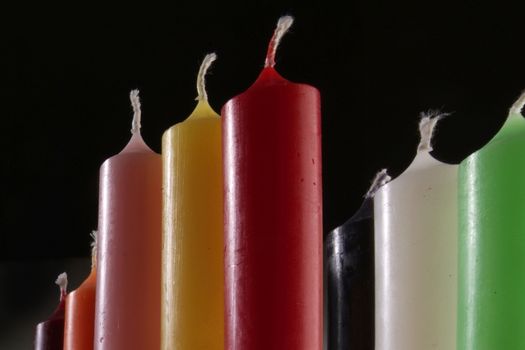 group of colorful cylindrical candles on a black background