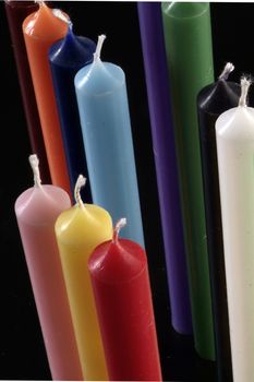 group of colorful cylindrical candles on a black background