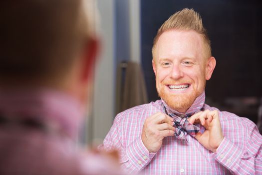 Happy European man with beard tying a bowtie