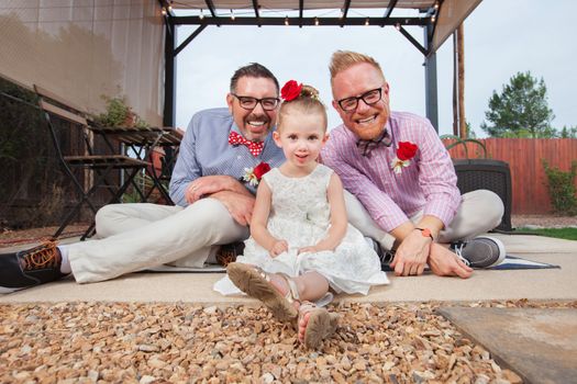 Happy same sex couple sitting with daughter outdoors