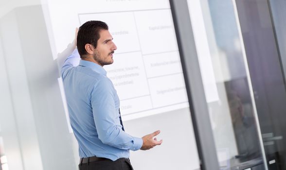 Business man making a presentation in front of whiteboard. Business executive delivering a presentation to his colleagues during meeting or in-house business training. 