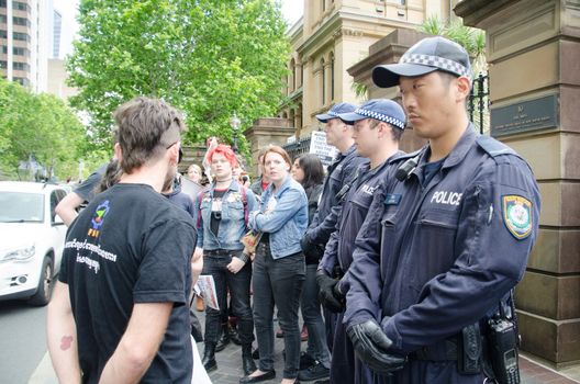 AUSTRALIA, Sydney: Police stand by as protesters gather outside the annual general meeting for Transfield at the Sydney Mint on October 28, 2015. People arriving for the AGM were heckled and jeered before protesters were forced to move on. Transfield operates detention centres on Nauru and Papua New Guinea's Manus Island. 