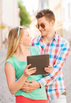 travel, vacation, technology and friendship concept - smiling couple with tablet pc computer in city