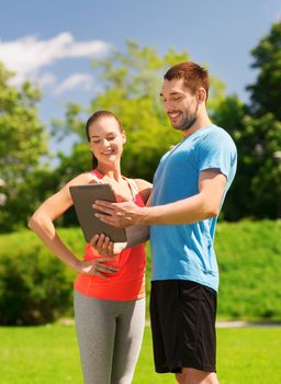 fitness, sport, friendship, technology and lifestyle concept - smiling couple with tablet pc computer outdoors