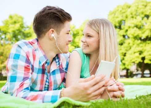 vacation, holidays, technology and friendship concept - smiling couple lying on blanket and making selfie with smartphone in park