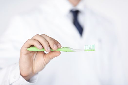 close up of male dentist or stomatologist holding toothbrush..