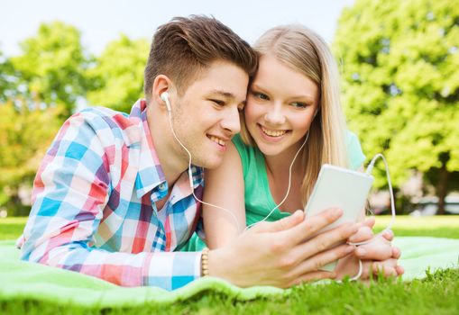 vacation, holidays, technology and friendship concept - smiling couple lying on blanket and making selfie with smartphone in park