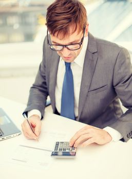 business, office, school and education concept - businessman with laptop computer, papers and calculator