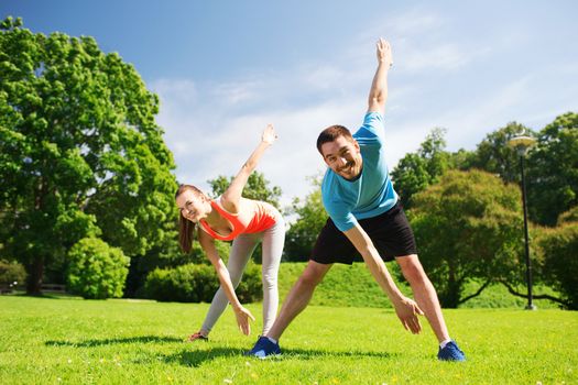 fitness, sport, training and lifestyle concept - smiling couple stretching outdoors