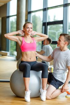 sport, fitness, lifestyle and people concept - smiling man and woman with exercise ball in gym