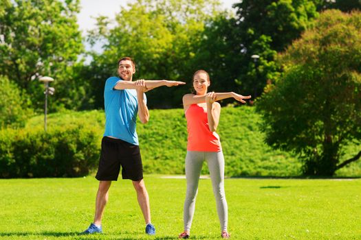 fitness, sport, training and lifestyle concept - smiling couple stretching outdoors