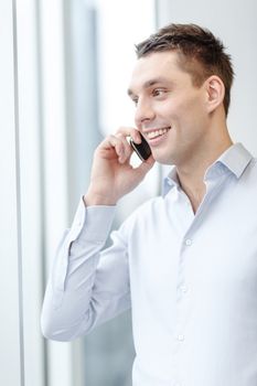 business, technology and office concept - smiling businessman with smartphone in office