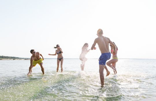 friendship, sea, summer vacation, holidays and people concept - group of happy friends having fun on summer beach