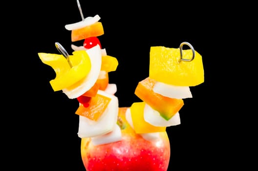 Vitamin-rich fruit skewers in an apple against white background.