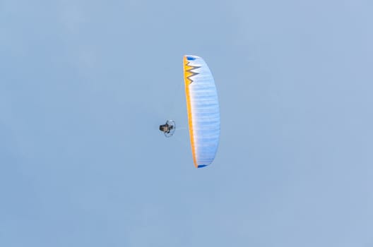 Paramotoring or microlight, paragliding against a blue sky.