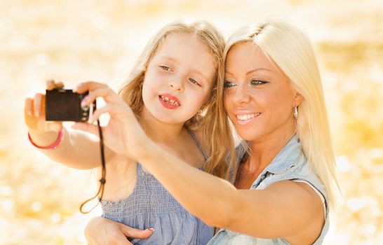 Beautiful, happy mother and daughter pose for a self portrait in the nature
