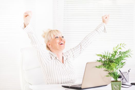 Cheerful Business woman sitting in the office with raising hands