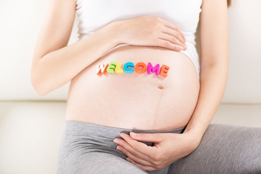 Welcome letters written on a pregnant belly.