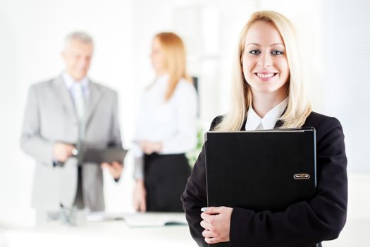 Happy Beautiful young businesswoman with documents standing in the office. Looking at camera. Selective Focus.