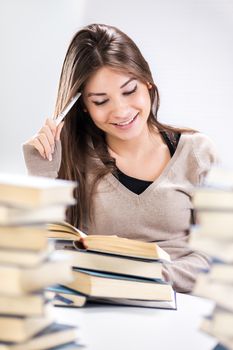 Beautiful Student girl learning and thinking between many books. Selective focus.
