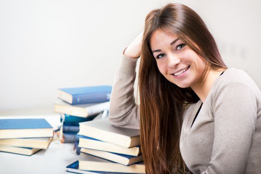 Portrait of Cute Young woman with many books. Looking at camera.