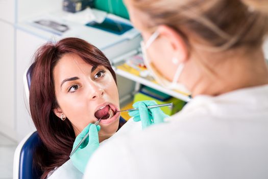 Dentist checking dental hygiene on patient mouth.