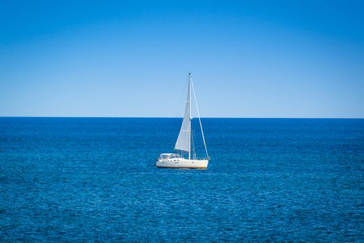 Small sailboat on the blue ocean in daylight