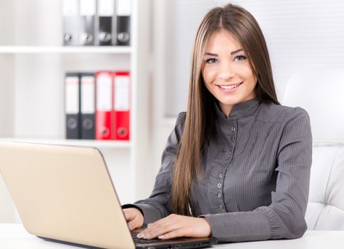Businesswoman in the office, sitting with laptop and Looking at camera.