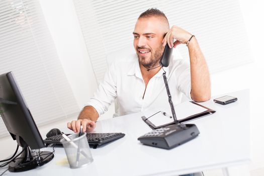 Attractive businessman sitting at the table and talking on the telephone