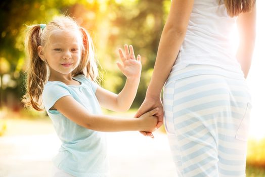 Mother and daughter holding hands during a walk on the park.