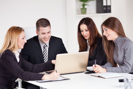 Four happy Business people looking project at laptop in the office.