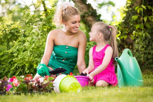 Beautiful mother and daughter planting flowers in the garden.