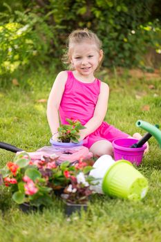 Smiling little girl planting flowers in the garden.