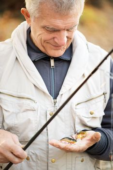 Senior Fisherman holding many Fishing lures.