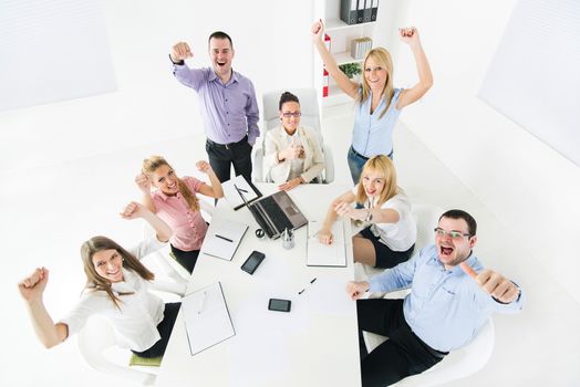 Group of a happy Successful Business People showing thumbs up and expressing positivity with raised arms.