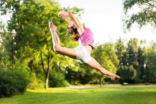 Beautiful young woman jumping in the park.