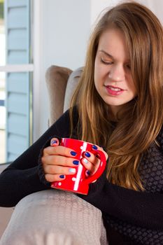 beautiful woman drinking coffee in the morning sitting by the window