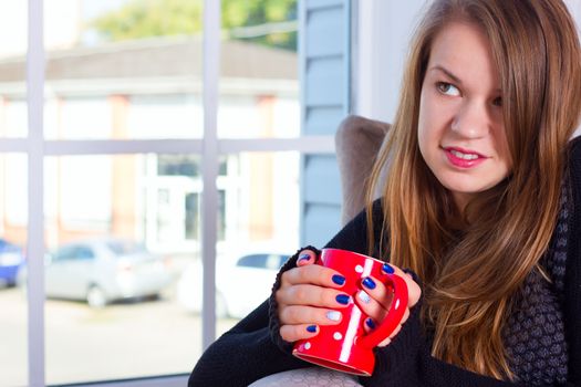 beautiful woman drinking coffee in the morning sitting by the window