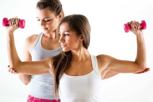 Young beautiful woman practicing upper body muscle group with personal trainer.