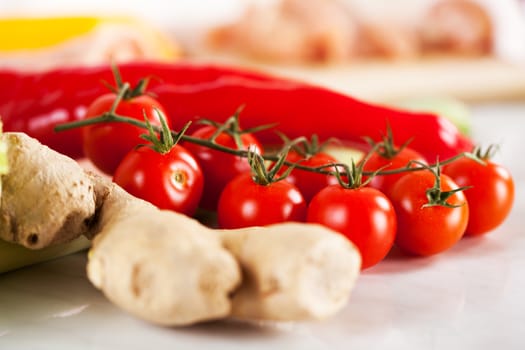 Red Cherry tomato with ginger and red peppers on the kitchen board.