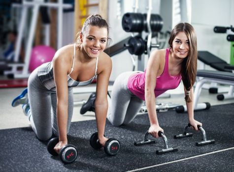 Cute Sporty girls doing exercise in a fitness center. Looking At Camera.